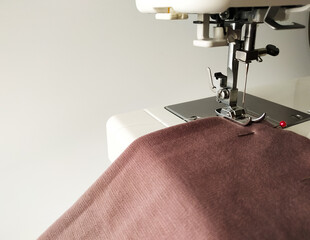 close-up of a white sewing machine with a knitted fabric on a white background.