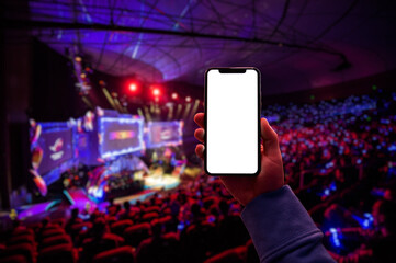 Using digital application on the mobile smart phone at esport event at big arena. Blank screen with copy space. © romankosolapov