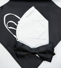 A new concept of style required for adapting to the times of coronavirus. Black bow tie and a whiterespirator. For everyday life or as an elegant wedding kit for a groom.