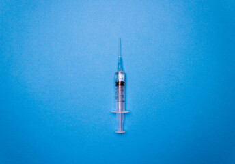 syringe vial dose of vaccine or another medicine with syringe on blue background with free copy space. Concept of vaccine against covid, virus vaccine