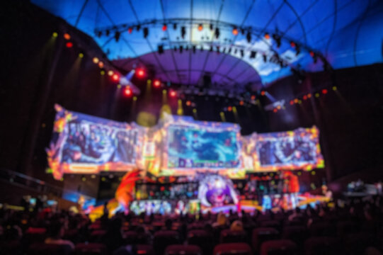 Blurred background of esports event at big arena with a lot of lights and screens.