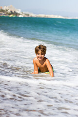 Fototapeta na wymiar a very happy child playing with the waves of the sea