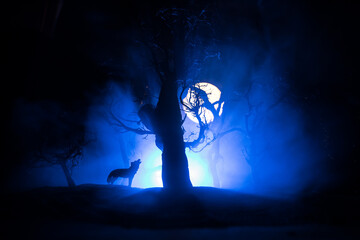 Silhouette of howling wolf against dead forest skyline and full moon. Creative artwork decoration.