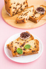 Homemade cake with raisins and dried persimmon on a pink pastel background. Side view, copy space.