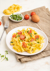Reginelle semolina pasta with tomato, eggs, sesame and microgreen sprouts on a white wooden background. Side view, close up.