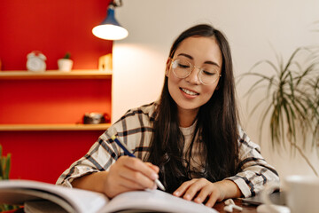 Girl student wearing glasses reads abstract with interest and underlines important words