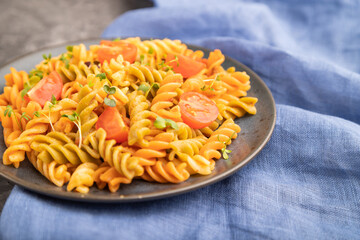 Tortiglioni semolina pasta with tomato and microgreen sprouts on a black concrete background. Side view, selective focus.