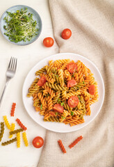 Tortiglioni semolina pasta with tomato and microgreen sprouts on a white wooden background. Top view, close up.