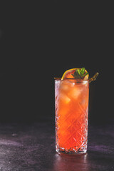 Pink Grapefruit Mezcal Paloma Cocktail in highball glass with water drops, dark background.