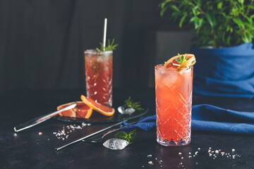 Pink Grapefruit Mezcal Paloma Cocktail in highball glass with water drops on table in real home....