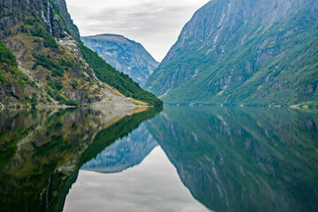 Fototapeta na wymiar Reflection of mountains on fjord surface at Naeroyfjord near Gudvangen