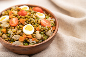Mung bean porridge with quail eggs, tomatoes and microgreen sprouts on a white wooden background. Side view, selective focus.