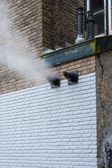 Vintage facade with white steam from ventilation system in the winter day
