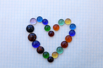 Heart made of small round pieces of glass on checkered paper.