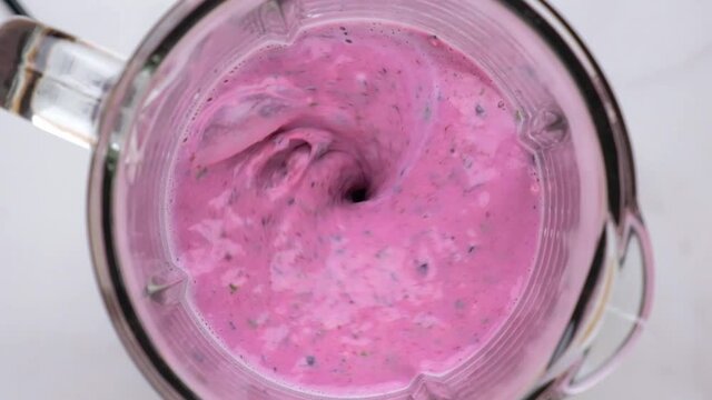 Blueberry smoothie or milkshake blended in blender with splashes. top view. slow motion. Healthy drink concept