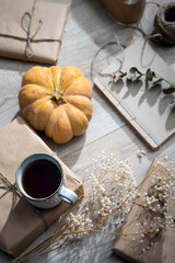 Packaged and bandaged gifts, pumpkins, a cup of tea and dried plants are on the table. Preparing for the birthday.