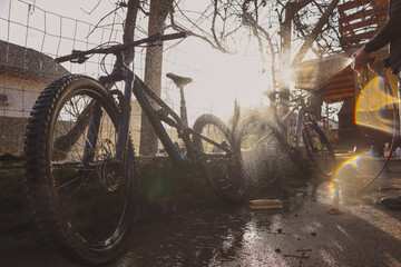 Person cleaning mountain bikes with the aid of a water jet. Panoramic dreamy photo of bicycle...