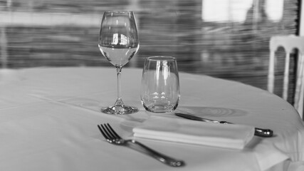 Mise en place, con calice da vino,  bicchiere, forchetta, coltello e tovagliolo in bianco e nero orizzontale