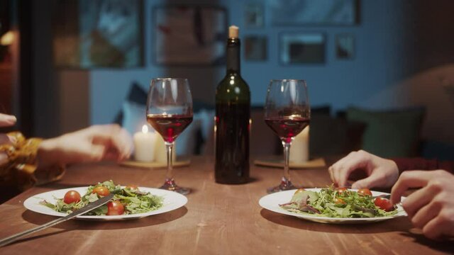 Young Couple in love dinner, talking and drinking red wine, cozy Saint Valentines Day celebration at home or in restaurant, students lovers, millennials romantic evening, happy family