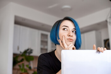 Smiling women with blue hair working long hours from her home office. Student girl working at home. Work or study from home, freelance, business.