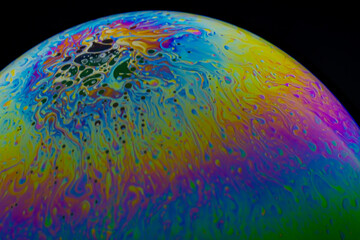 Close up, macro shot of a rainbow, multi colored soap bubble with yellow, purple, pink, blue and...