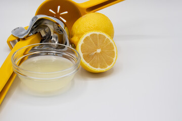 Lemon juicer with a lemon, a slice of lemon, and a dish of freshly squeezed juice