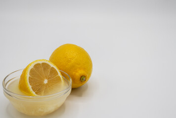 Close up of a lemon and a half lemon in a dish of freshly squeezed juice