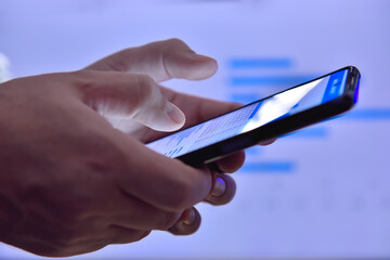Hands using smartphone with  financial data.