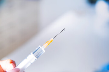 Needle of a syringe with a visible drop, closeup.