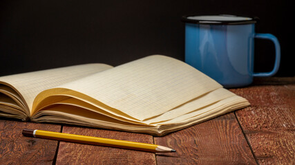 old blank notebook or travel journal opened on a rustic wood table with a metal cup of tea