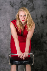 Fototapeta na wymiar blonde in a red dress leaned on a chair