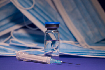 Vaccine bottle phial with no label and medical syringe with injection needle on background of blue...