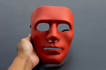 Hand holding face mask on dark background.