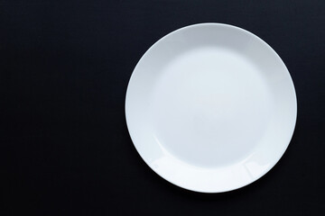 Empty white dish plate on dark background.