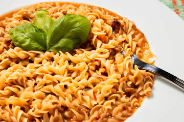 Traditional pasta fusilli with tomato sauce and basil. Close-up selective focus. 45 deg. view