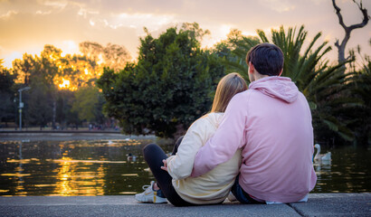 Couple sitting and hugging on the shore of a lake at sunset