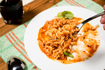 Plate of traditional pasta with tomato sauce eaten not finished, fork with pasta. Selective focus. Traditional food concept.