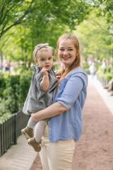 Fototapeta premium A young mother walks with a one-year-old baby. What to do while walking with your child
