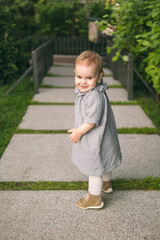 One year old baby girl in the mousline dress on the path in the park