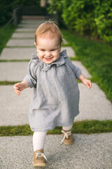 One year old baby girl in the mousline dress on the path in the park