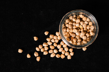 Dried chickpeas in a glass jar on a black surface. TOP view