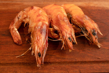 Close-up of a three whole shrimps cooked on the grill on a table.