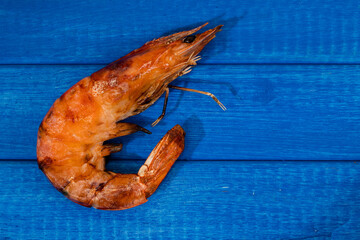 Close-up of a whole shrimp cooked on the grill on a light blue board. Home cooking, natural food concept