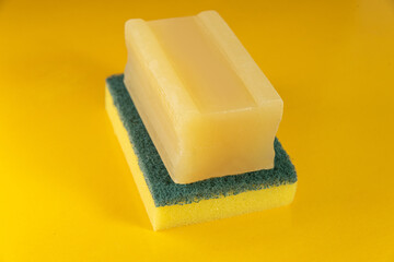 Kitchen sponge and soap bar on the yellow background