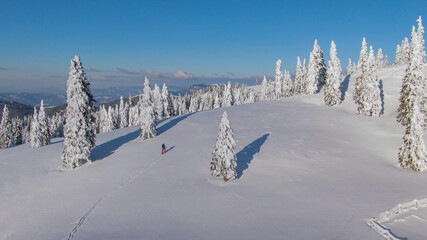 AERIAL: Spectacular flying shot of the wintry landscape surrounding ski tourer.