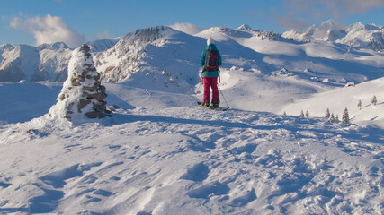 Naklejka na ściany i meble Unrecognizable female ski tourer observes landscape after reaching mountaintop.