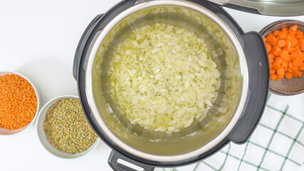 Saute chopped onion in multi cooker. Close up view from above