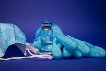 Vaccine bottle phial with no label, medical syringe with injection needle, blue medical mask and...