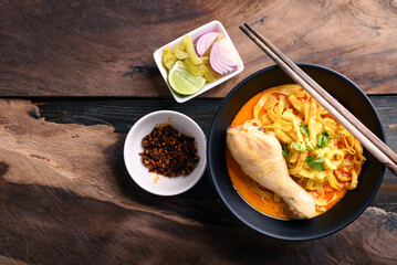 Northern Thai food (Khao Soi), Spicy curry noodles soup with chicken eating with crispy deep-fried egg noodles, pickled mustard, shallots, lime and ground chilies in oil