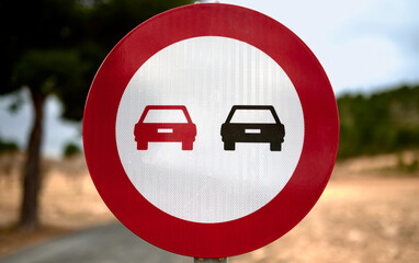 no overtaking traffic sign with blue sky and trees in the backgr